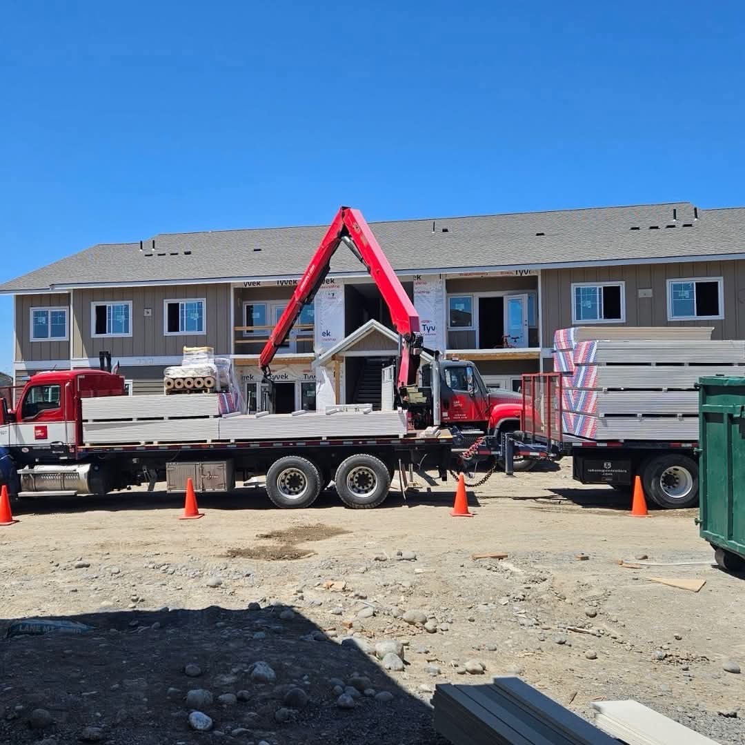 Commercial construction site with delivery trucks — large-scale drywall project